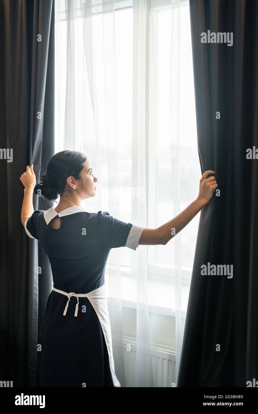 Das junge Zimmermädchen stand am Fenster im Hotelzimmer Stockfoto