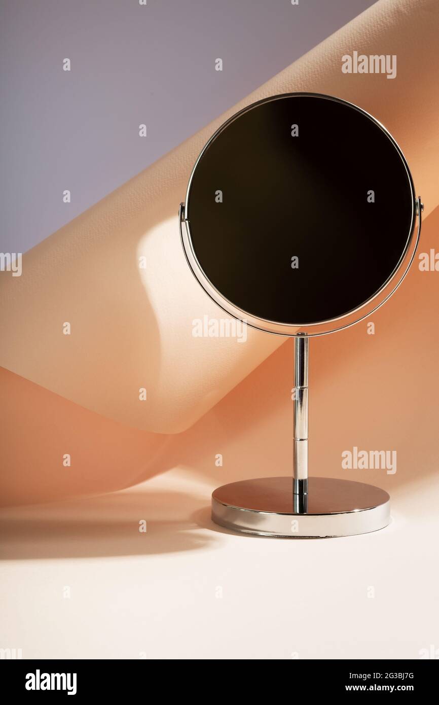 Silberner Kosmetikspiegel auf dem Tisch. Speicherplatz kopieren. Fokus auf Schatten Stockfoto