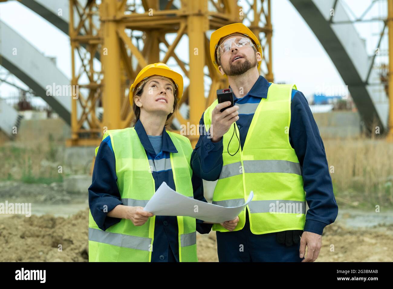 Zwei junge Bauherren blicken während der Bauarbeiten nach oben Stockfoto
