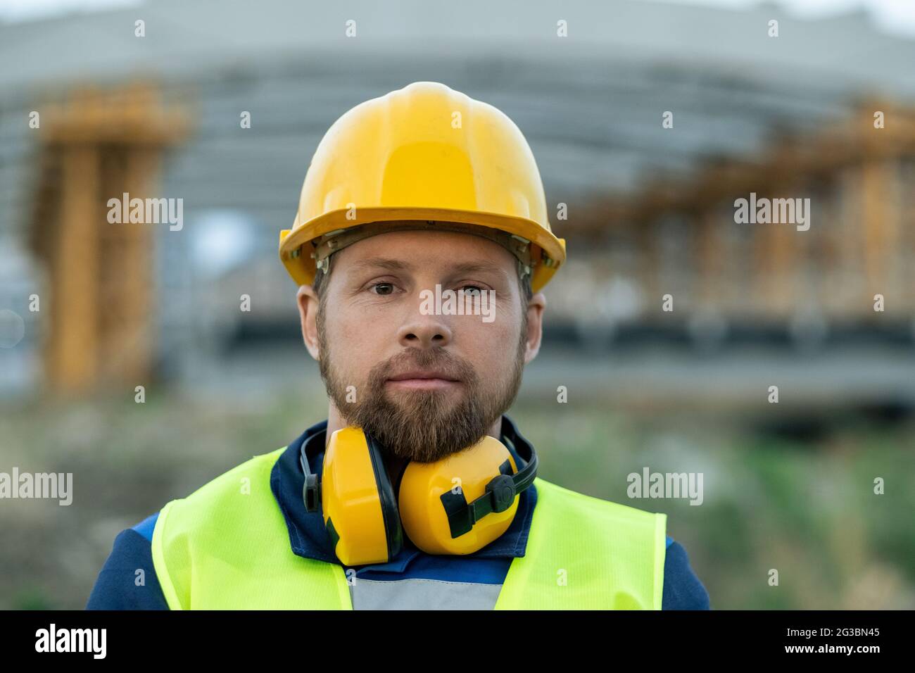 Junge seriöse Ingenieur oder Baumeister in Hardhat und Arbeitskleidung Stockfoto