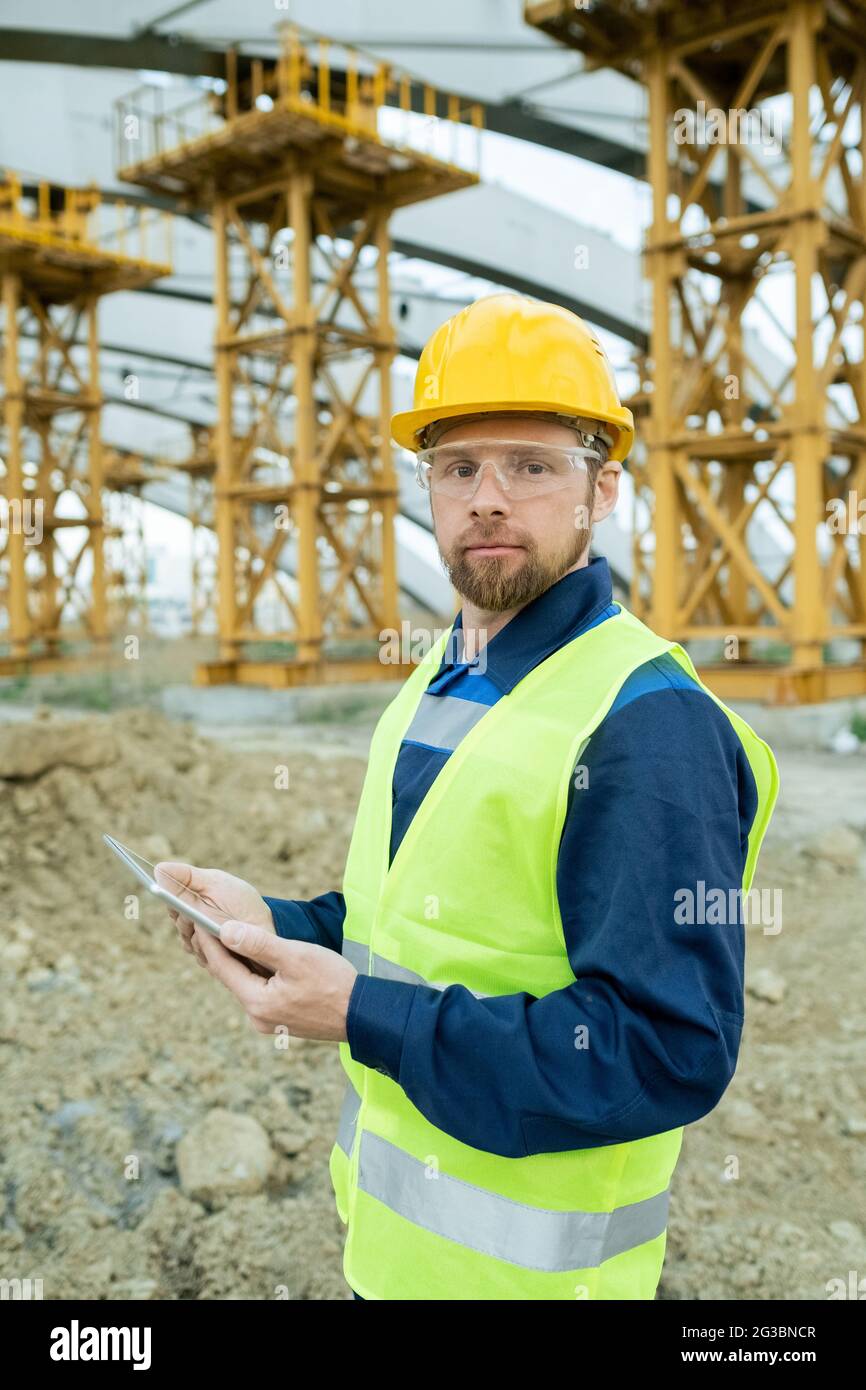 Serious Builder in Uniform und Hardhat mit Tablet und Blick auf Sie Stockfoto