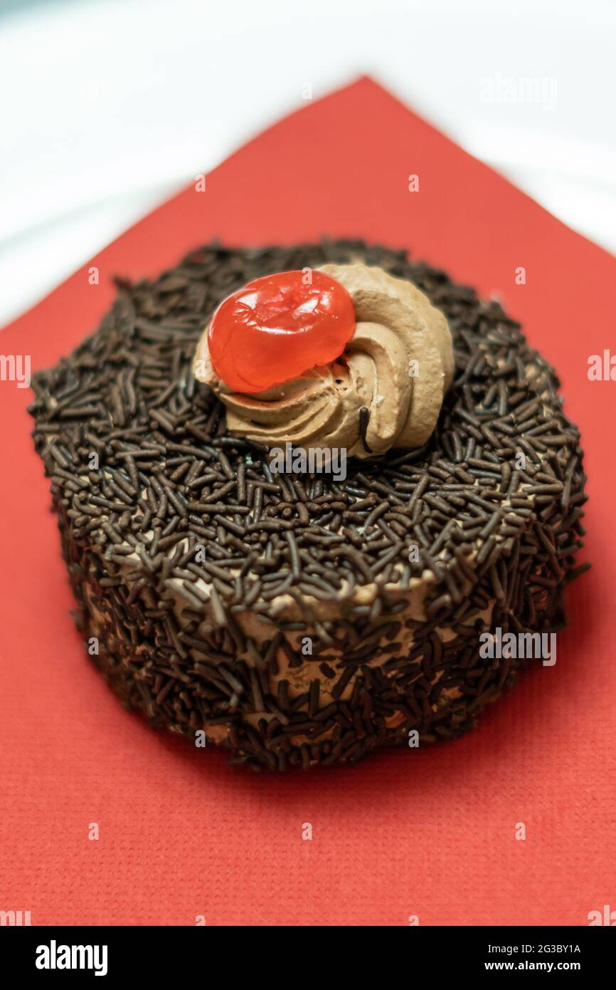 Cupcake mit Schokoriegel und Sahnehahne mit Kirsche Stockfoto