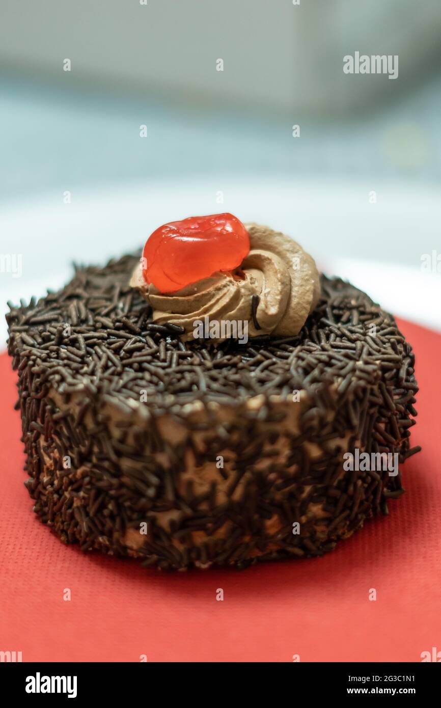 Cupcake mit Schokoriegel und Sahnehahne mit Kirsche Stockfoto