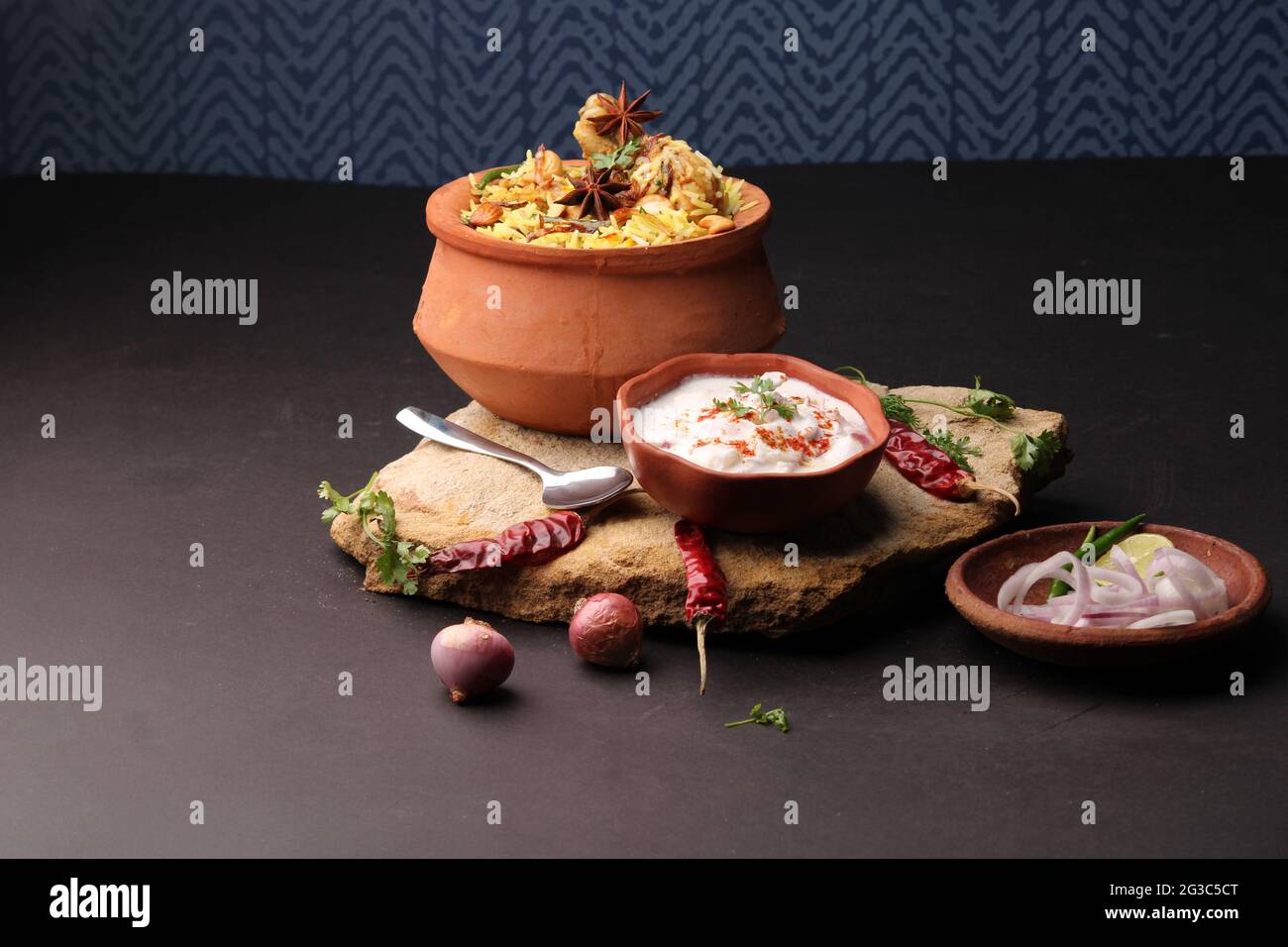 Würziges Hähnchen Dum biryani in traditionellem Handi- oder Tontopf. Serviert mit Zwiebelraita Stockfoto