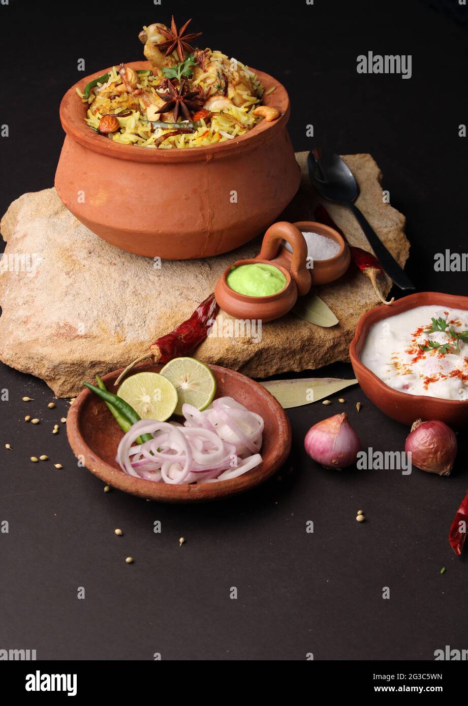 Würziges Hähnchen Dum biryani in traditionellem Handi- oder Tontopf. Serviert mit Zwiebelraita Stockfoto