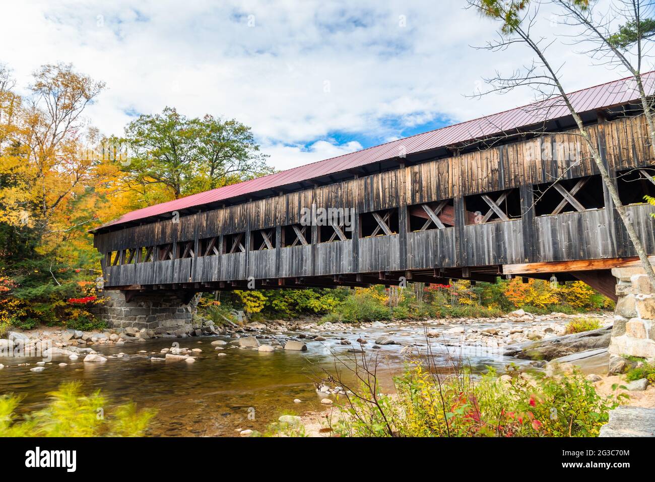 Historische hölzerne überdachte Brücke über einen Bergfluss an einem bewölkten Herbsttag. Herbstfarben. Stockfoto