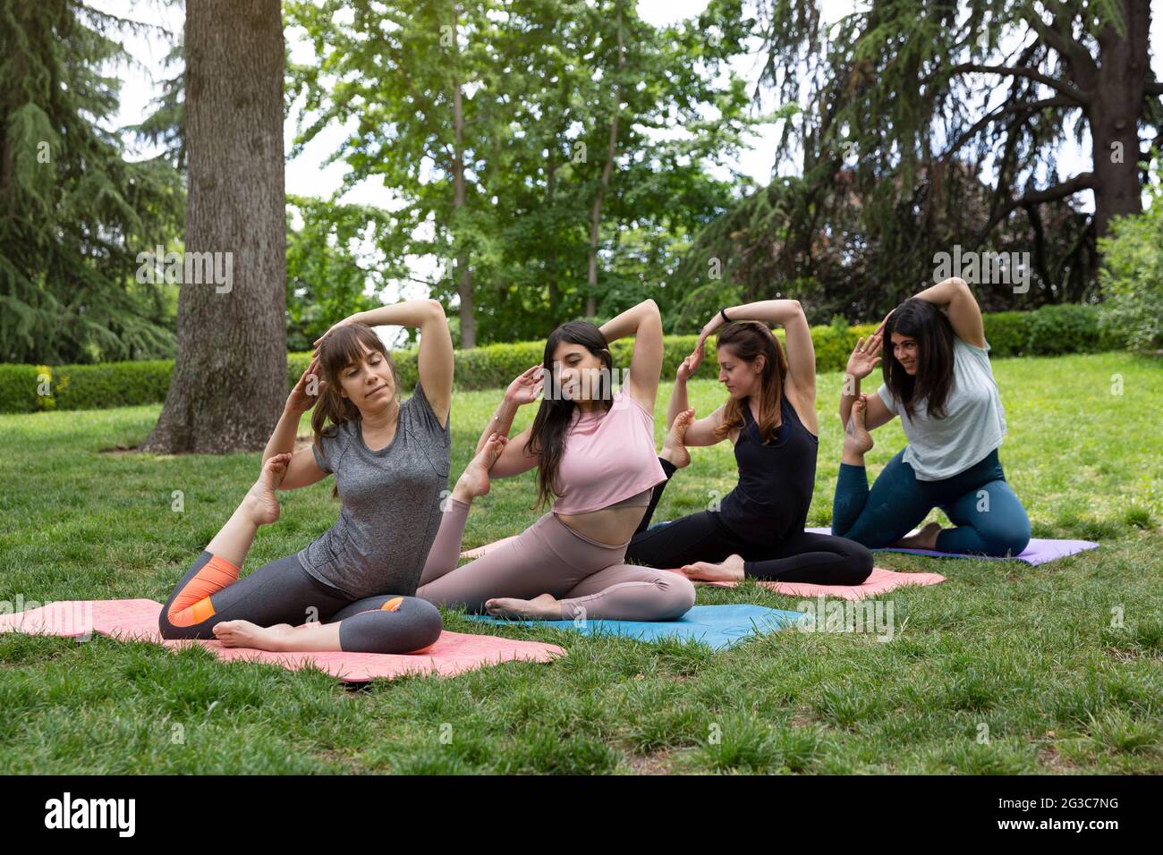 Vier Frauen konzentrieren sich auf Yoga-Haltung im Freien. Platz für Text. Stockfoto