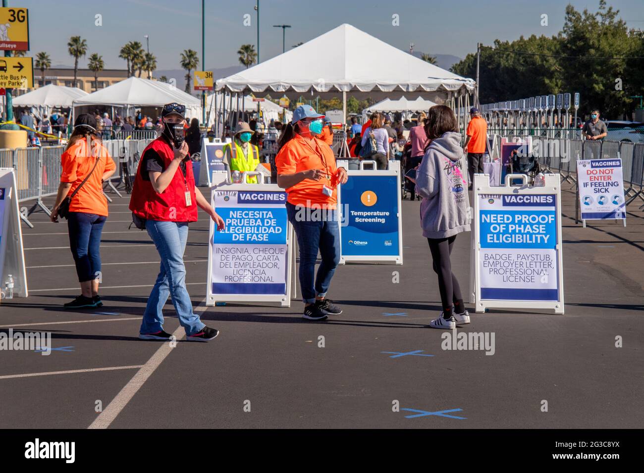 Multirassische Freiwillige, die medizinische Masken tragen, haben direkten Zugang zu einer Impfstelle für Coronaviren auf einem Parkplatz in Anaheim, CA. Stockfoto