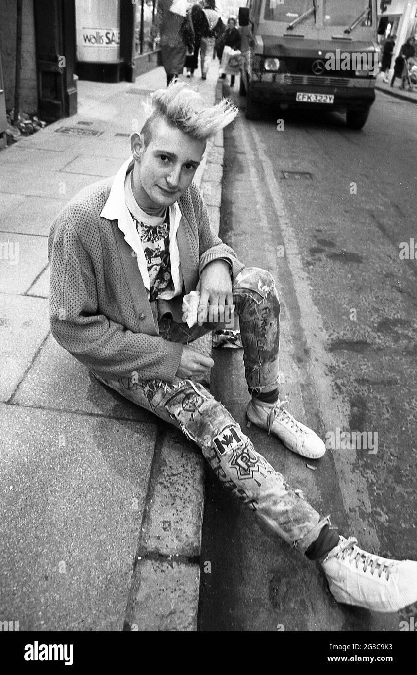 1980er Jahre Ein Junger Mannlicher Punk Der Draussen Auf Einem Burgersteig In Einer Stadtstrasse England Grossbritannien Siitiert Punk Rock Oder Einfach Punk War Ein Musikgenre Das Mitte Der Spaten 1970er Jahre Entstand