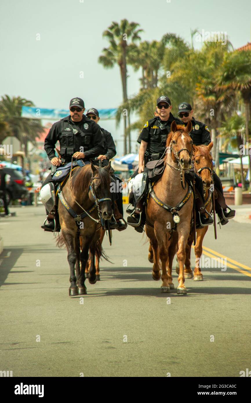 Berittene Polizisten kommen in Huntington Beach, CA, zur Massenkontrolle bei einer geplanten politischen Demonstration an. Stockfoto