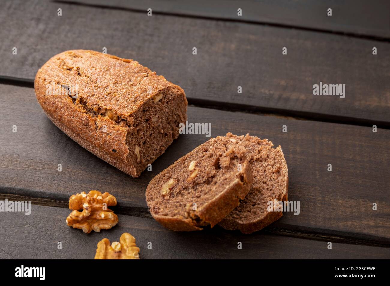 Scheiben Nussbaumsauerteig Brot auf dunklem Holzhintergrund mit Kopierraum Stockfoto