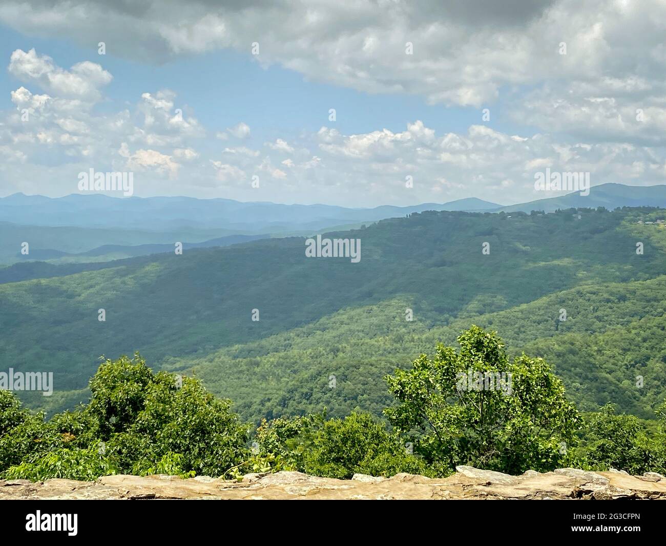 Blick auf die Berge und den Himmel von einer Steinbarriere aus, die Wolken und weite Ausblicke zeigt Stockfoto