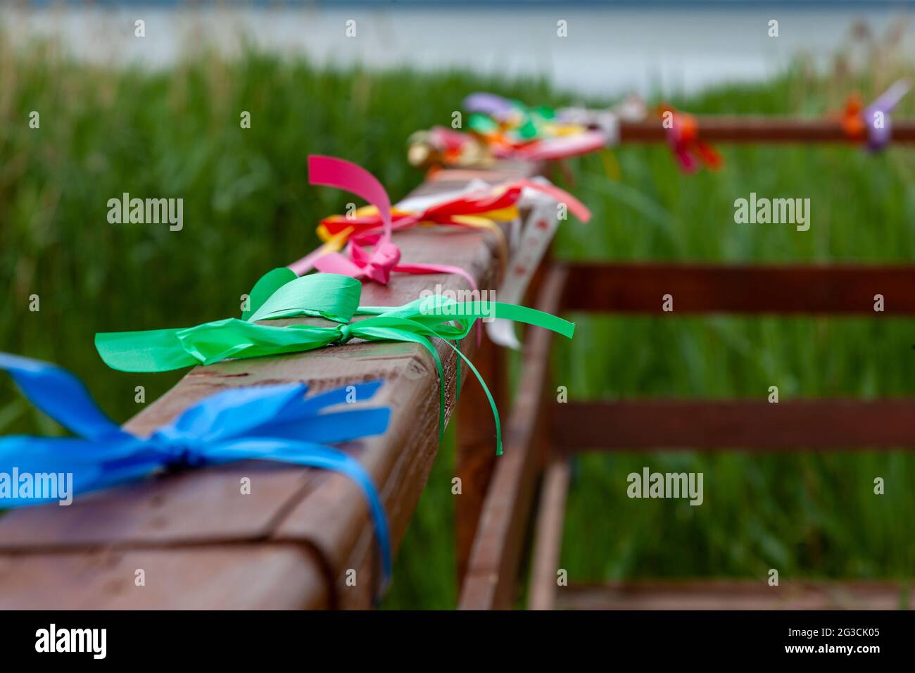 Mehrfarbige Bänder, die an das Holzgeländer der Brücke gebunden sind. Stockfoto