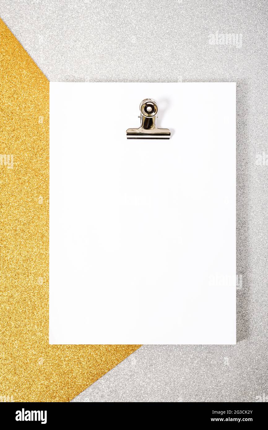 Weißes Folienpaket und Büroklammer auf silberfarbenem und goldfarbenem Hintergrund. Das Foto hat einen Kopierbereich, es wird aus der Sicht von oben und aufgenommen Stockfoto