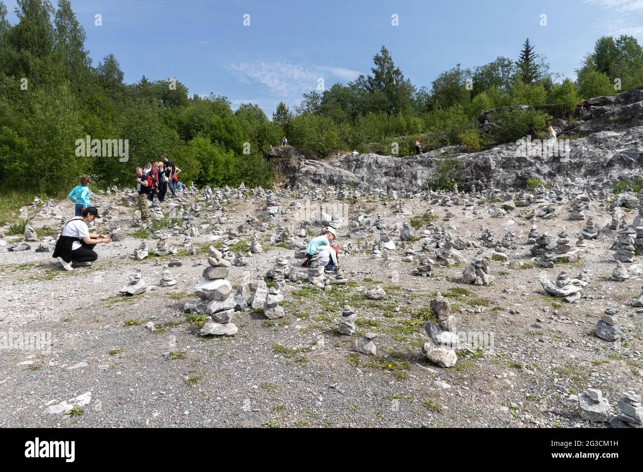 Ruskeala, Russland - 12. Juni 2021: Touristen bauen steinhaufen im ehemaligen Marmorbruch im Ruskeala Mountain Park Stockfoto