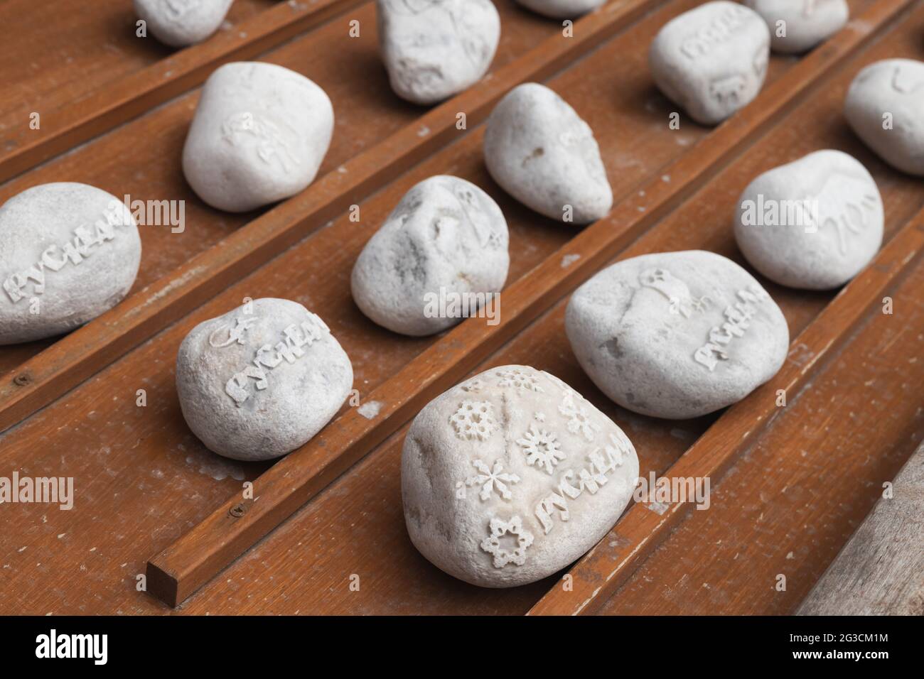 Ruskeala, Russland - 12. Juni 2021: Weiße Marmorsteine mit dekorativen Schnitzereien liegen auf einer Theke des Souvenirshows. Text bedeutet Ruskeala Stadtnamen in Rus Stockfoto