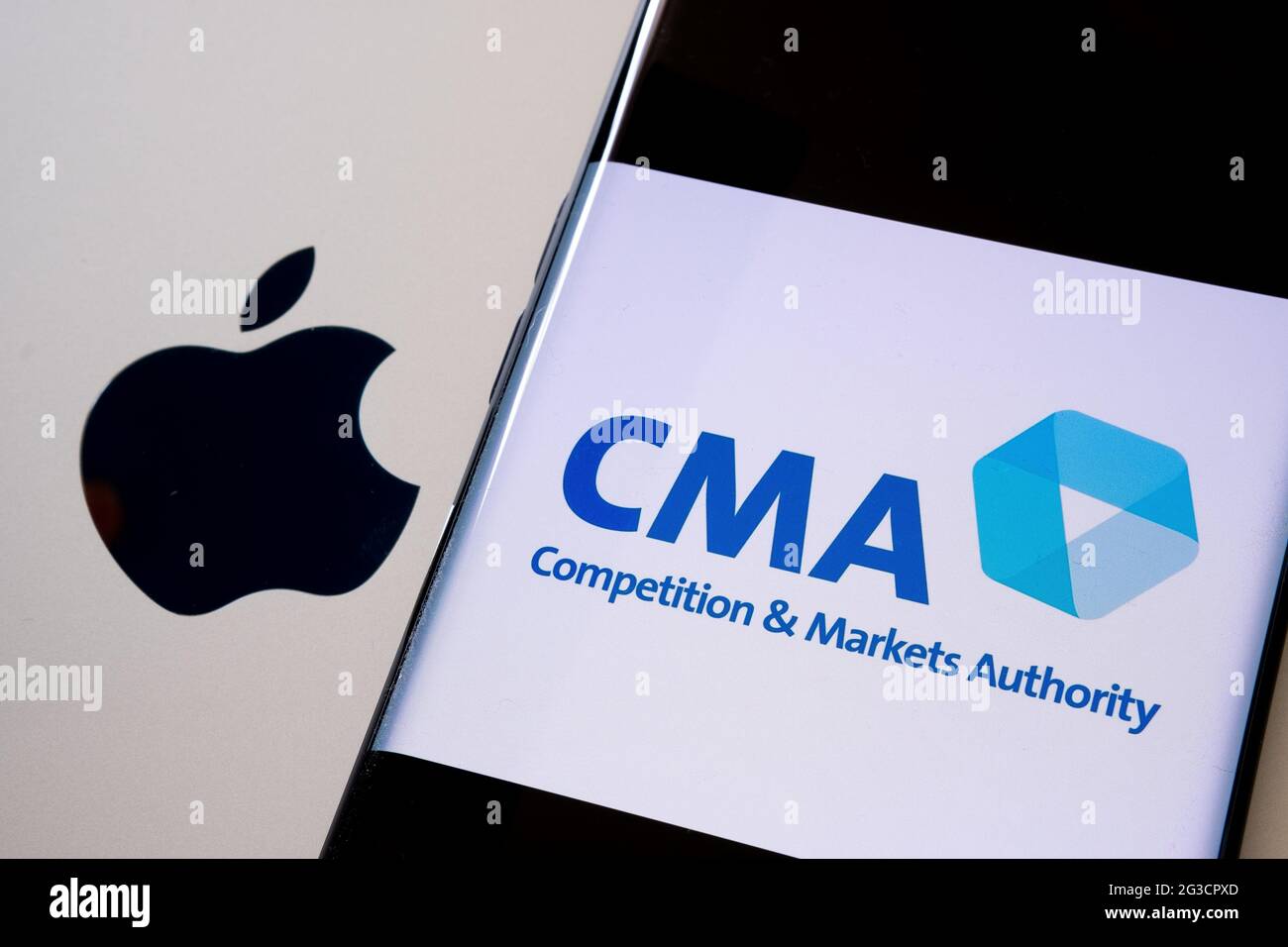Apple-Logo auf macbook Oberfläche und verschwommenes UK CMA Competition and Markets Authority-Logo auf dem Smartphone-Bildschirm. Konzept. Stafford, United King Stockfoto