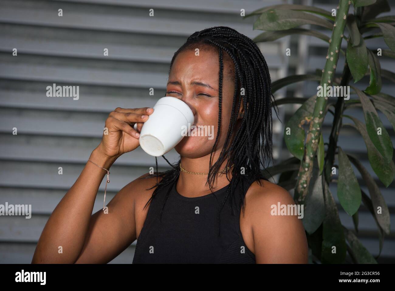 Gestresste Geschäftsfrau trinkt Kaffee mit Ekel und Übelkeit auf der Außenseite. Stockfoto