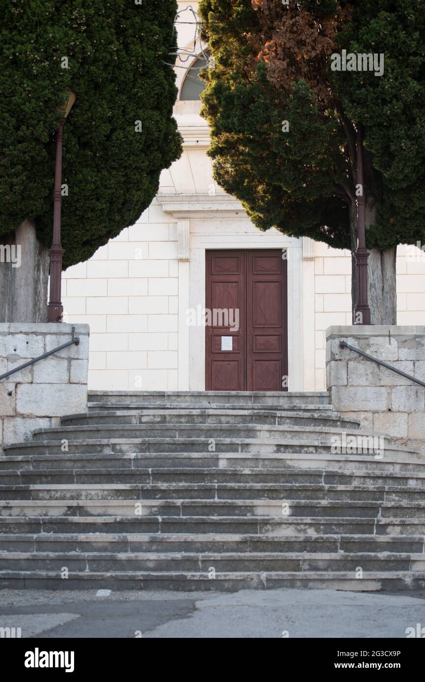 Vertikale Aufnahme einer breiten Treppe zu einem weißen Steingebäude mit Eingangstür in der Mitte Stockfoto