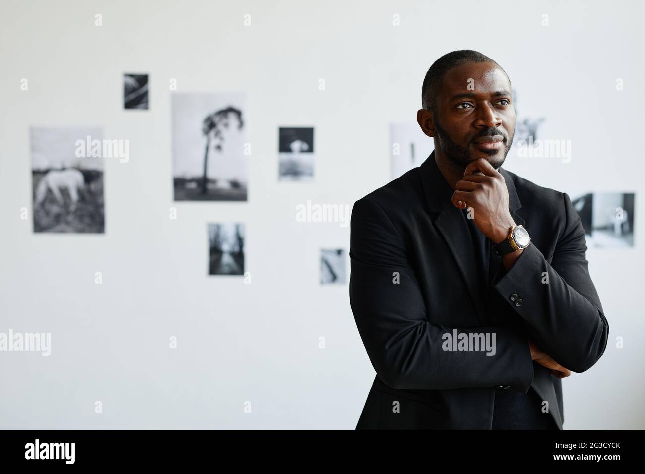 Minimal Taille up Porträt des eleganten afroamerikanischen Mann in schwarz, während Blick auf Fotos in der modernen Kunstgalerie, Copy Space Stockfoto