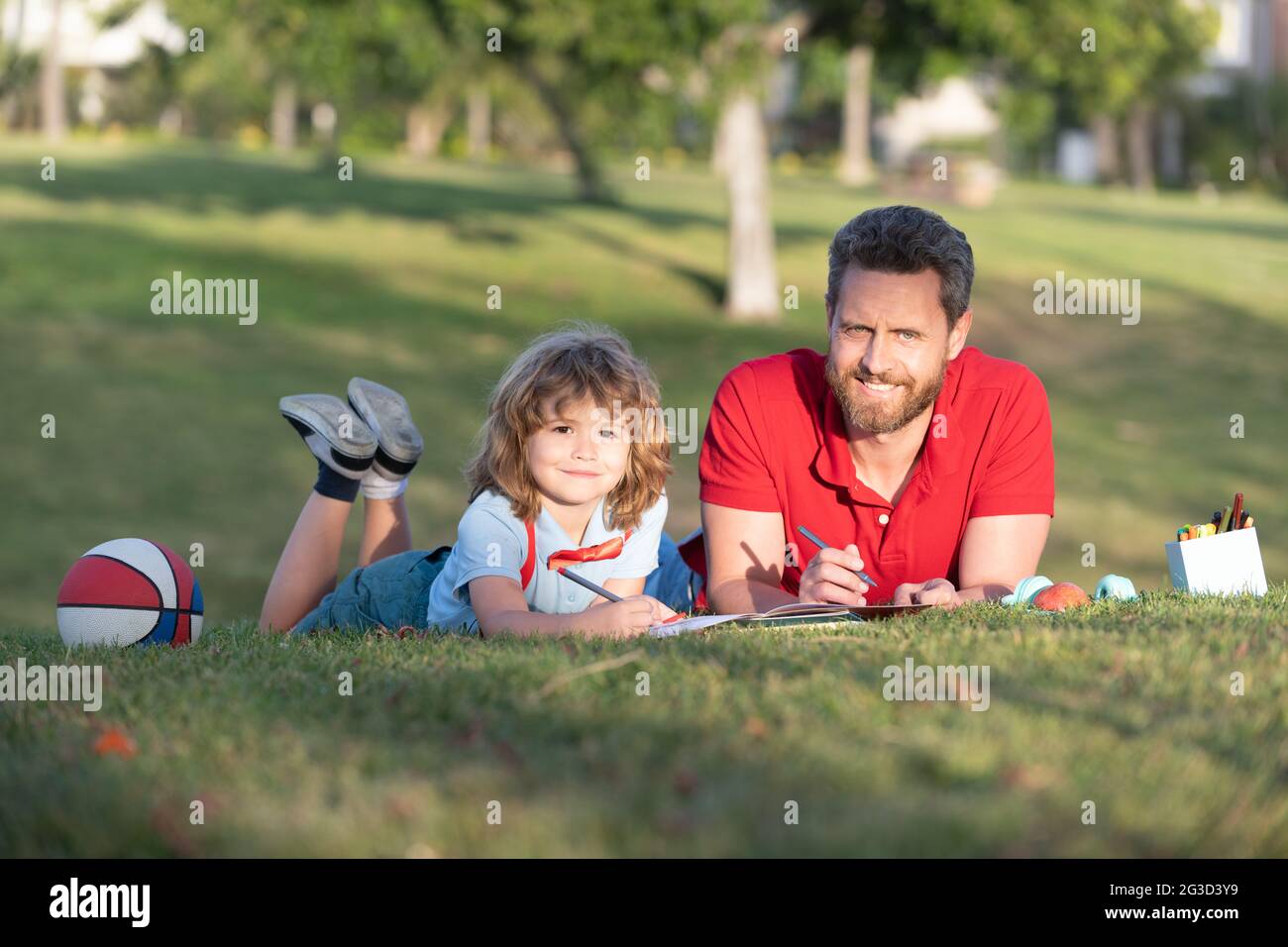 Vater und Sohn entspannen sich auf Gras im Park lernen zu zeichnen, Familienwochenende Stockfoto