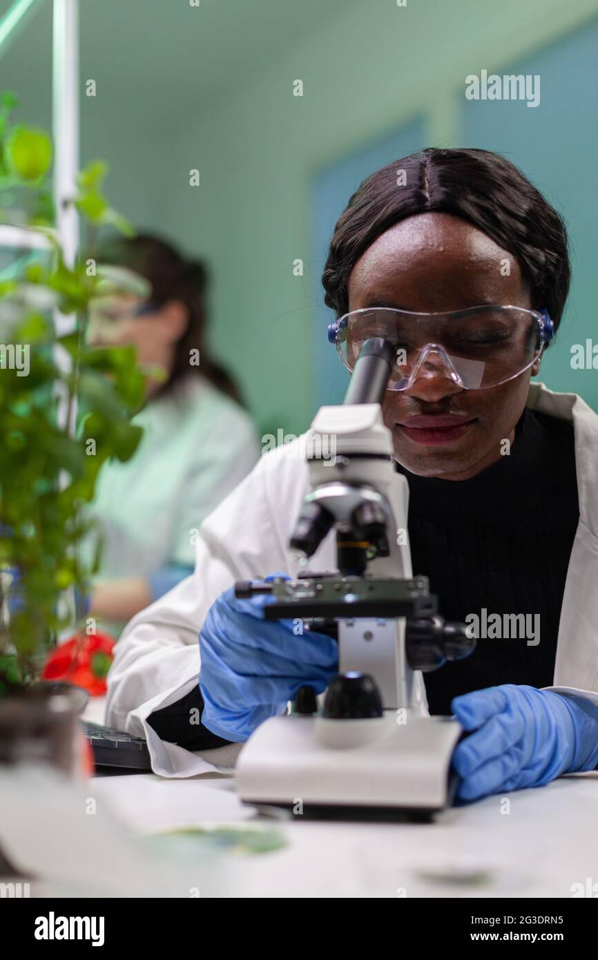 Biologe Forscher Wissenschaftler betrachten Blattprobe unter einem medizinischen Mikroskop, während sie biologische Expertise auf Notizblock schreiben. Chemiker untersucht biologische Entdeckungen im Labor für Mikrobiologie. Stockfoto