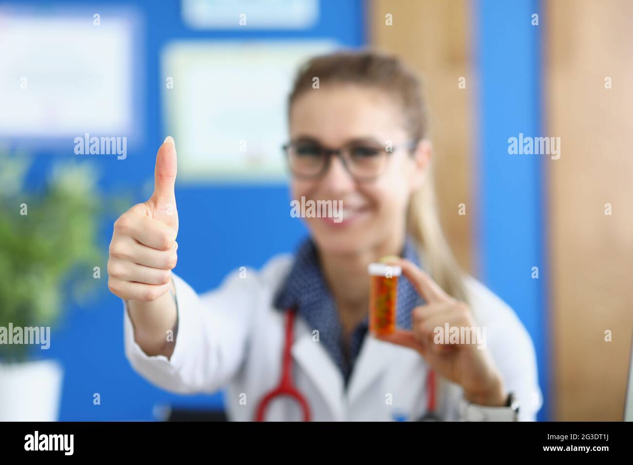 Lächelnde Ärztin zeigt Daumen nach oben und hält Medikamente Stockfoto