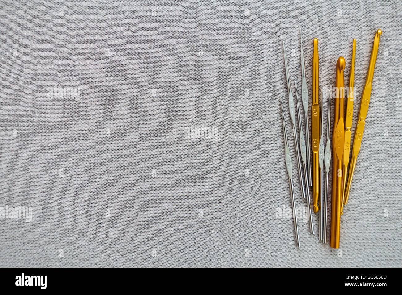 Häkelnadeln, Häkelnadel, Shepherds' Haken, in Silber und Gold, auf einem grauen Hintergrund Kopierraum. Stockfoto
