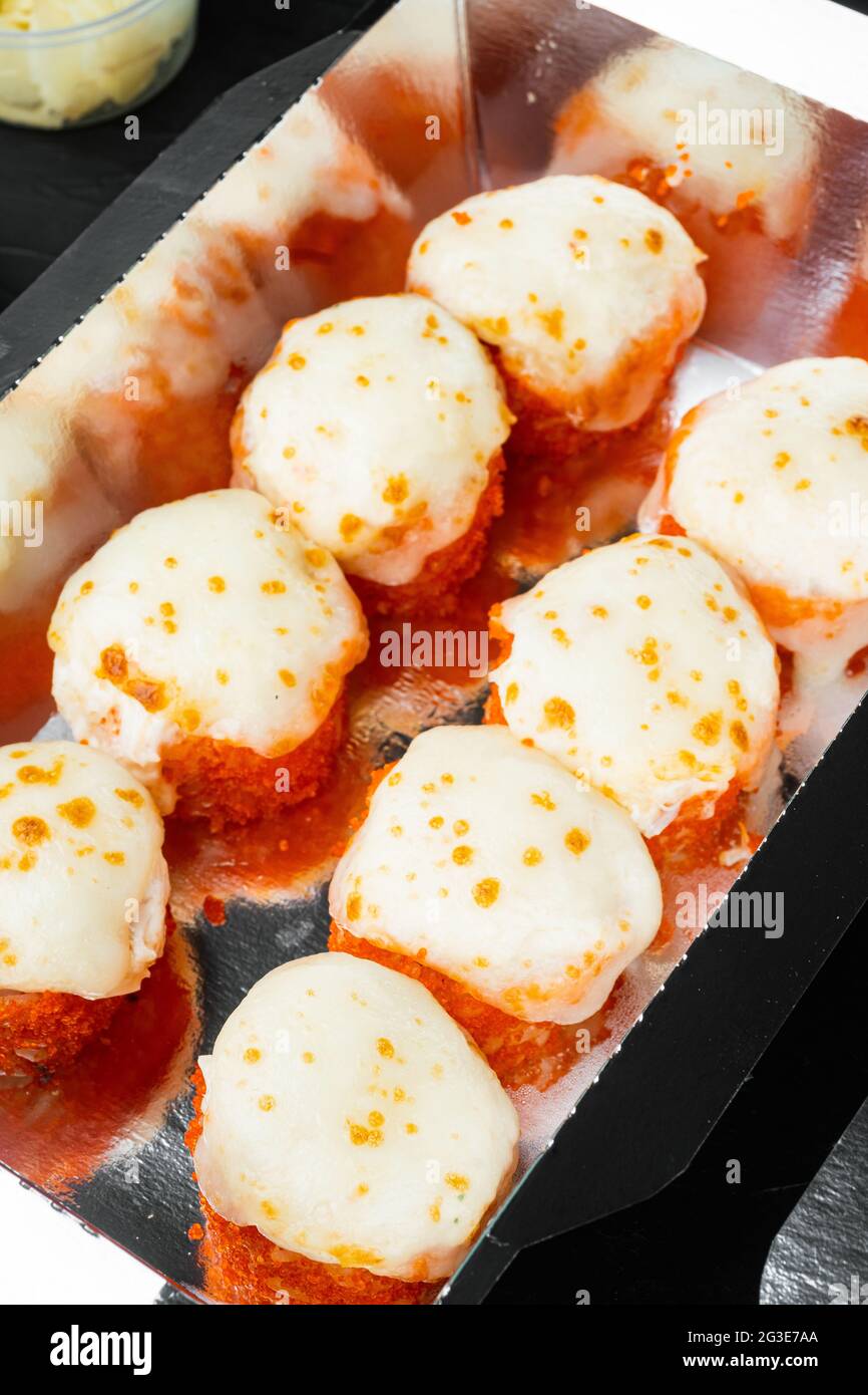 Set von Sushi-Rollen in Lieferkarton, auf schwarzem Steinhintergrund Stockfoto