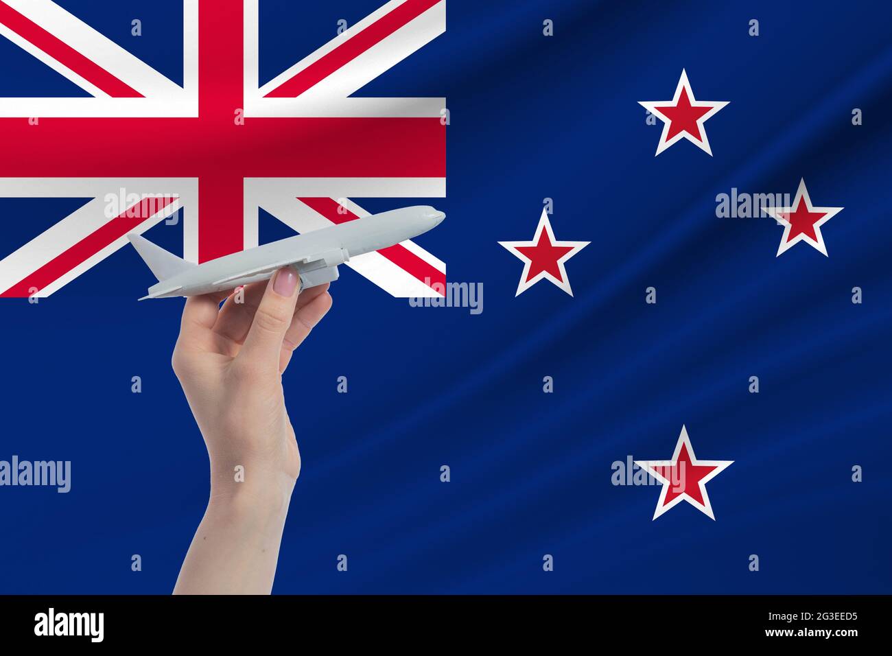 Flugzeug in der Hand mit der Nationalflagge Neuseelands. Reise nach Neuseeland. Stockfoto