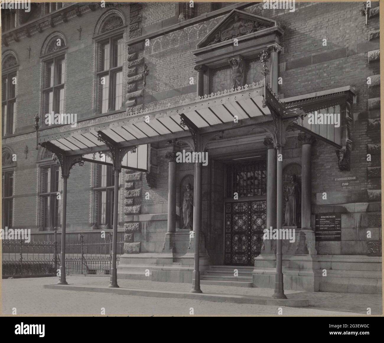 Osteingang mit Markise; Osteingang in der Nordfassade. Eingang auf der Nordseite des Turms II mit Zugangstür und Vordach auf gusseisernen Säulen. Auf beiden Seiten der Tür befinden sich Bilder von Frauen, über der Markise befindet sich ein Käfig unter einem Pauken mit dem Text Holländisches Museum. Links ist ein Teil der façade-Fassadenwand I-II Stockfoto