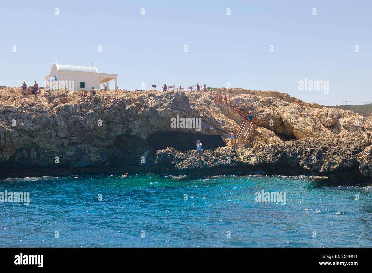 Protaras, Zypern - 21. Juli 2015: Touristen an der felsigen Küste von Cape Cavo Greco mit der Ayii Anargyri Kirche (EINE funktionierende orthodoxe Kirche mit einem c Stockfoto