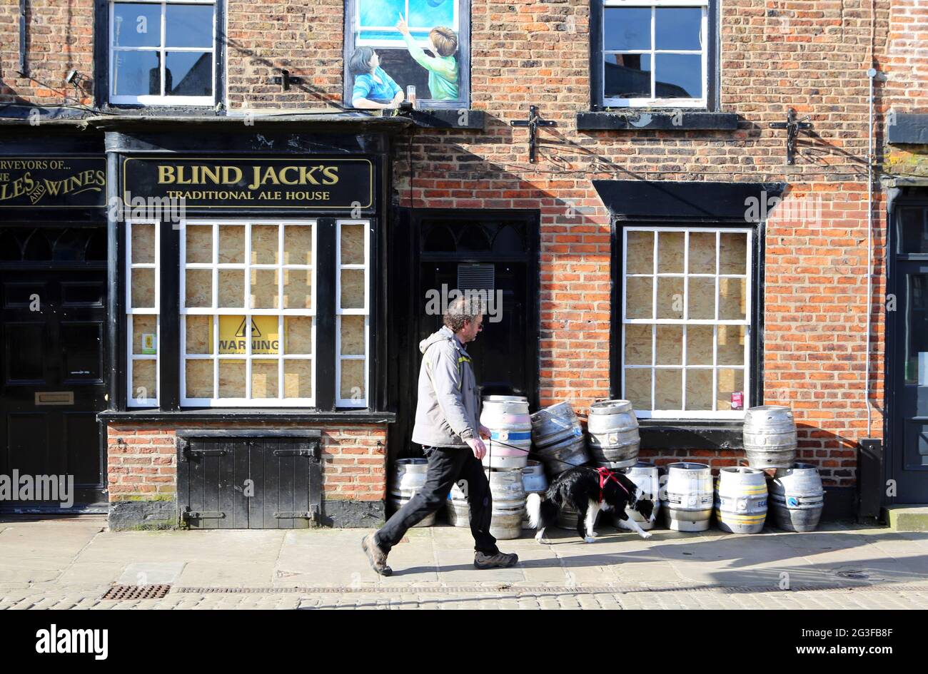 Ein Mann und sein Hund laufen an den leeren Bierfässern vor dem traditionellen Ale House von Blind Jacks in Knaresborough im Norden von Yorkshire vorbei, als Pubs, Bars und in Stockfoto
