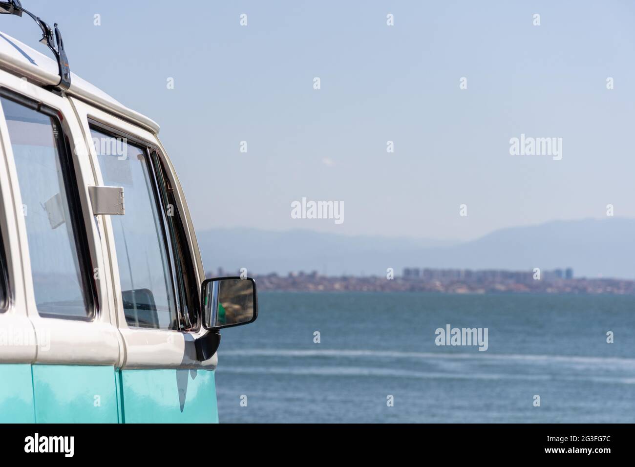 Nahaufnahme des türkisfarbenen Volkswagen-Van, der in der Nähe des Strandes geparkt ist, Sommerferienkonzept. Stockfoto