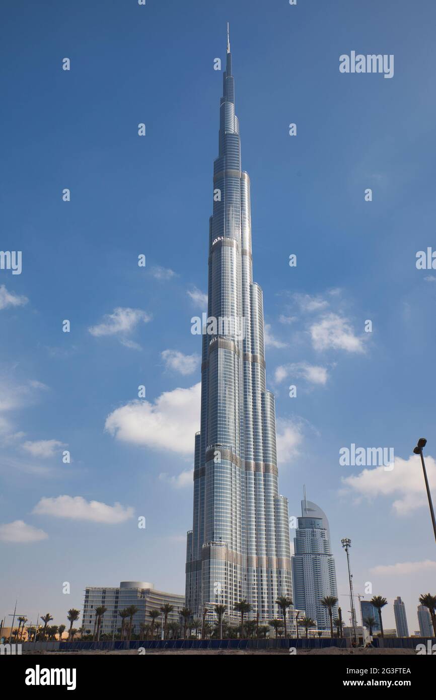 Das höchste Gebäude der Welt, der Burj Khalifa in Dubai, die Vereinigten Arabischen Emirate.Palmen und Skyline der Stadt im Vordergrund und blauer Himmel im Hintergrund & weiße Wolken Stockfoto