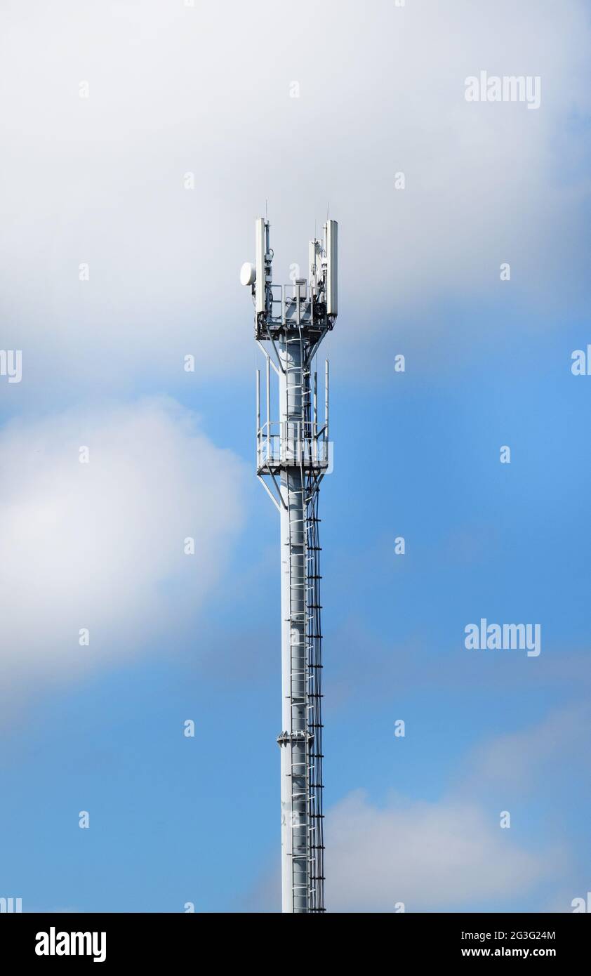 Telekommunikationsturm mit Antennen auf einem Hintergrund von blauem Himmel und Wolken. Intelligente Antennen übertragen 4G und 5G Mobilfunksignale an Verbraucher. Stockfoto
