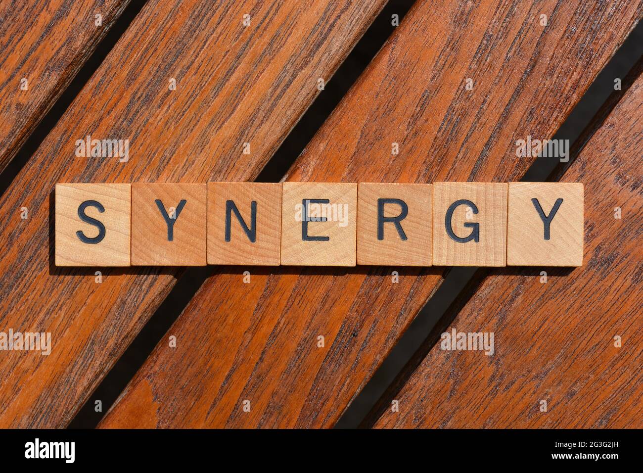 Synergy, Geschäftsbuzzword in hölzernen Buchstaben auf Teakholz Hintergrund Stockfoto