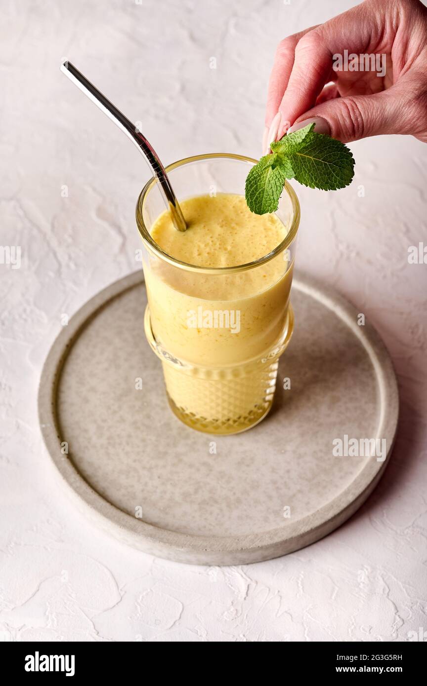 Woman Hand hält Minze auf Lassi ist ein traditionelles indisches kaltes erfrischendes Getränk. Löscht den Durst bei heißem Wetter perfekt Stockfoto