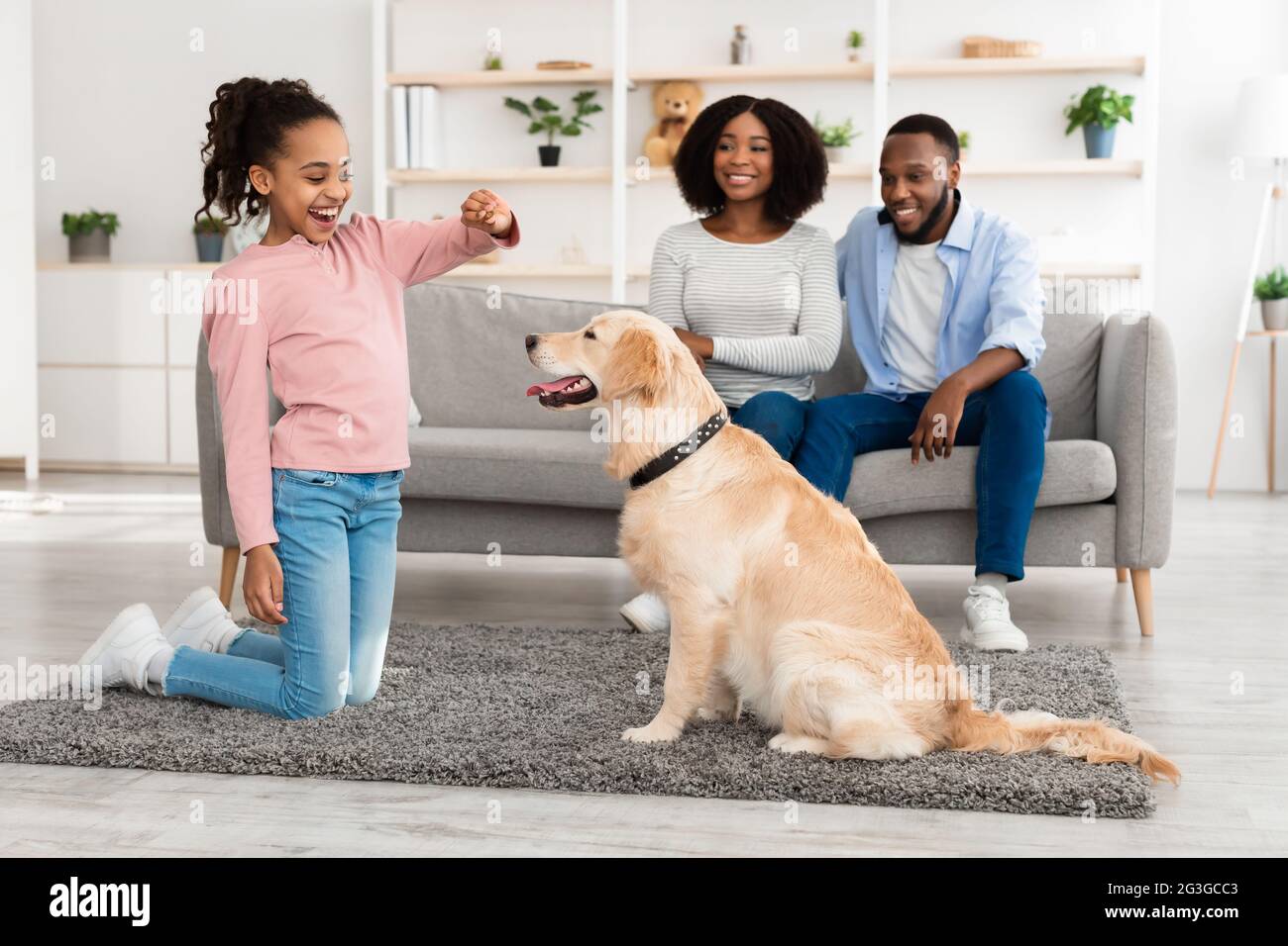 Happy black girl giving a treat to her labrador Stockfoto