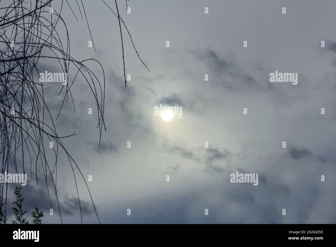 Echte blasse Sonne durch Wolken am grauen Himmel am bewölkten Tag Stockfoto