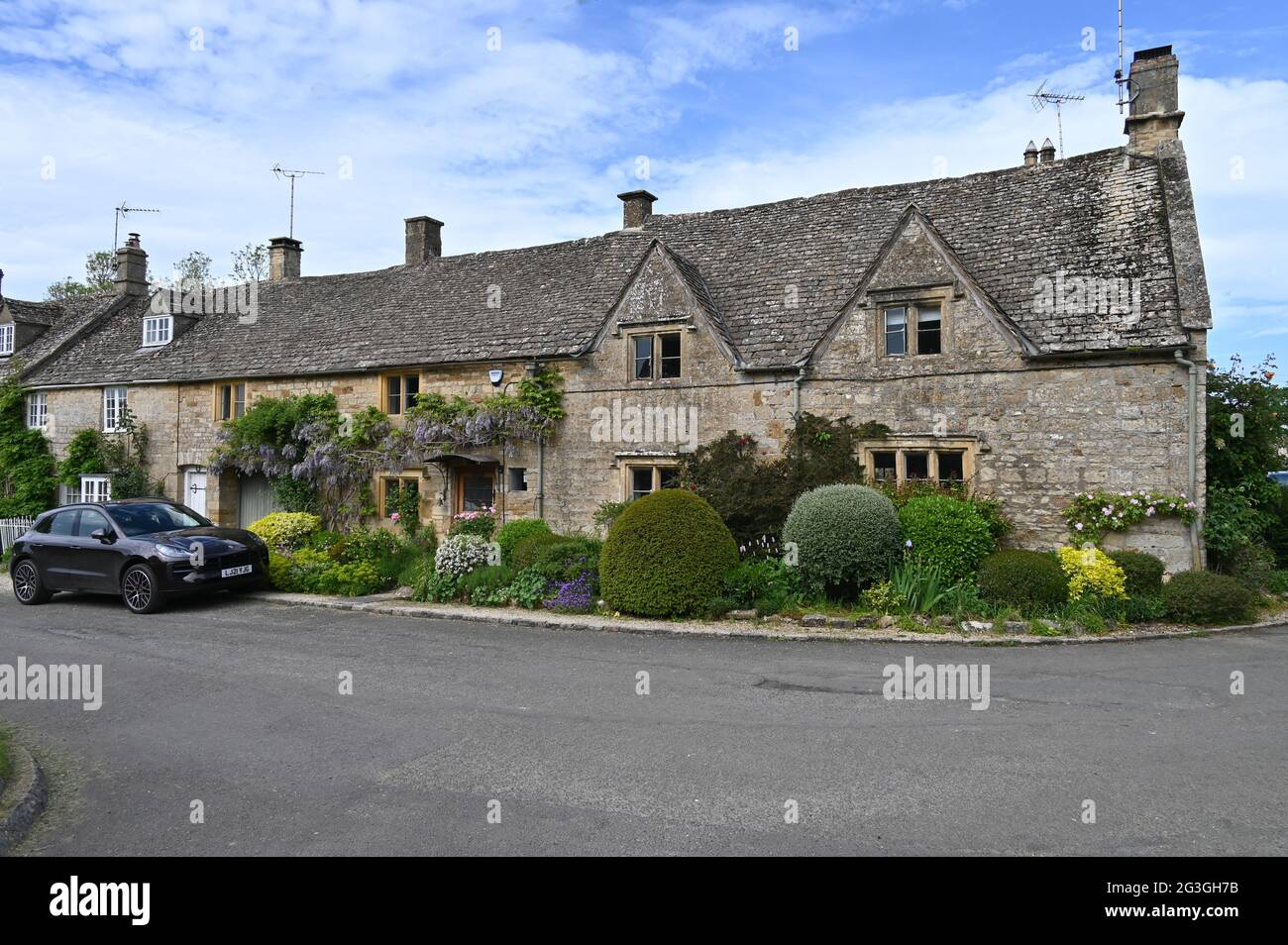 Glyzinien in Blüte, die an der Außenseite eines Hauses in Bledington, Gloucestershire, wachsen Stockfoto