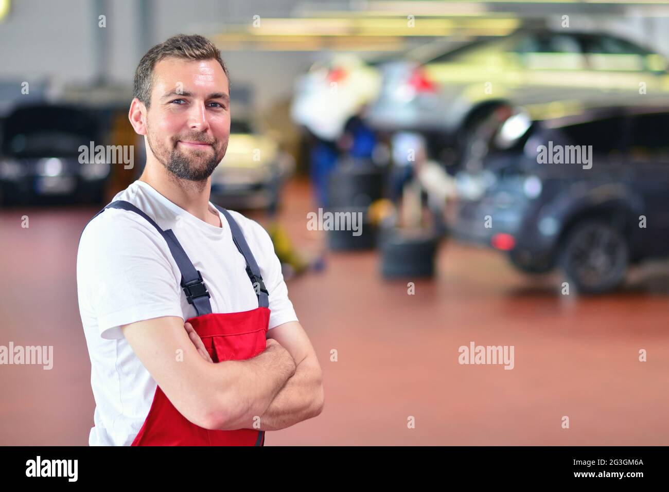 Porträt eines lächelnden Mechanikers in einer Autowerkstatt - Diagnose und Fehlersuche Stockfoto