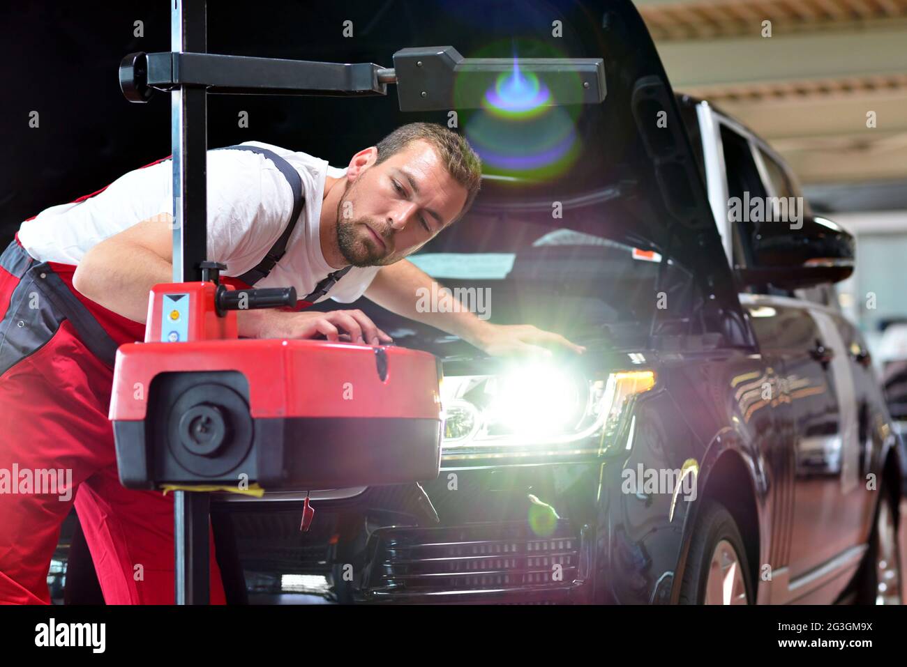 Autowerkstatt - Arbeitnehmer überprüft und passt die Leuchtweite der Beleuchtung ist ein Auto Stockfoto