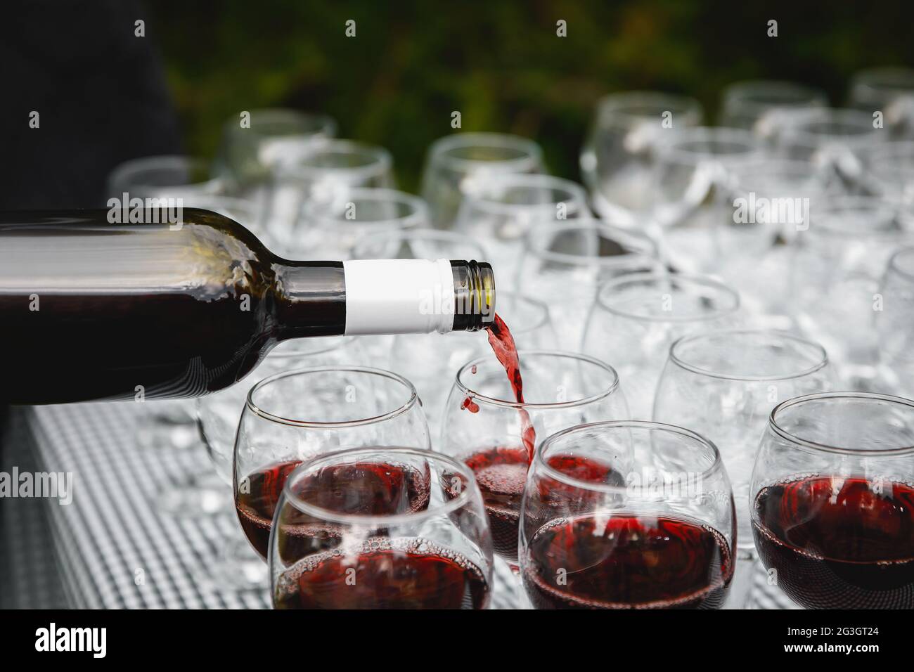 Der Kellner gießt Rotwein in das Glas Stockfoto