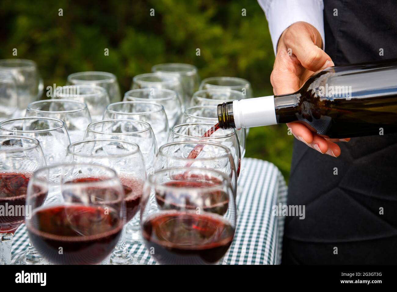 Der Kellner gießt Rotwein in das Glas Stockfoto
