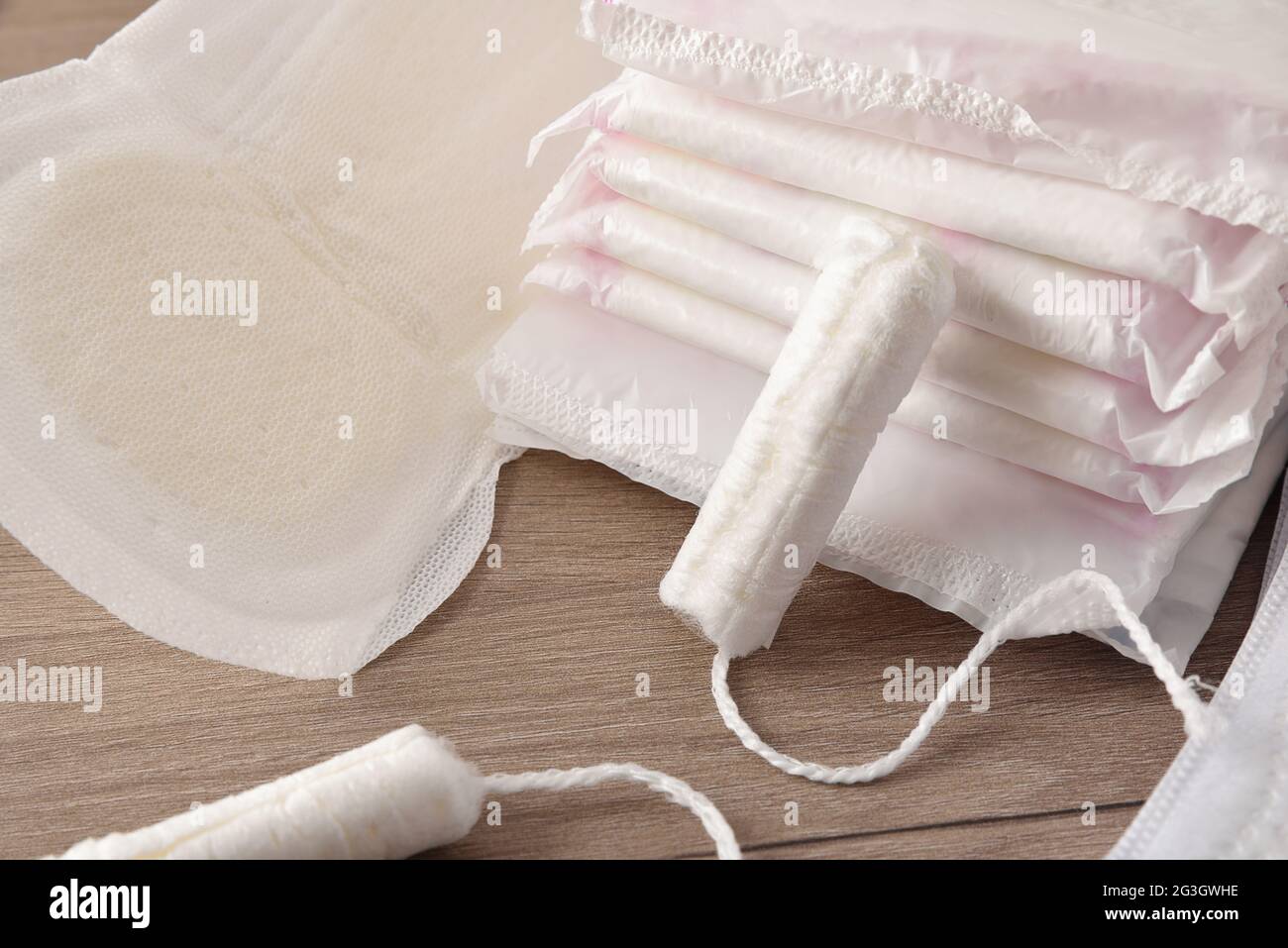 Saugfähige Menstruationspolster und Tampons. Serviette und Tampon auf Holztisch. Erhöhte Ansicht. Horizontale Zusammensetzung. Stockfoto