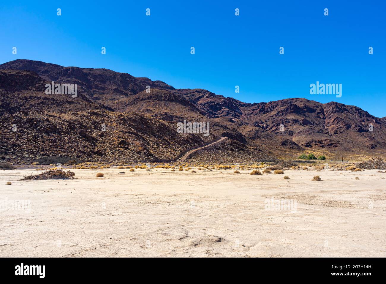 Dunkelbrauner Wüstenberg mit Wanderweg in der Mojave-Wüste Stockfoto