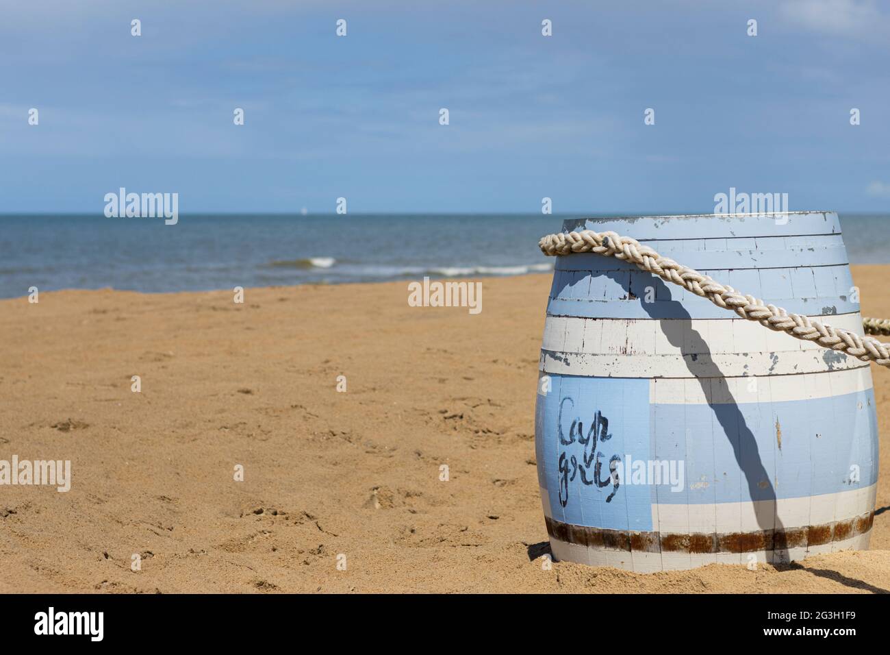 Ein ziemlich sonniger Tag an der belgischen Küste, vorne ein blau-weißes Fass Stockfoto