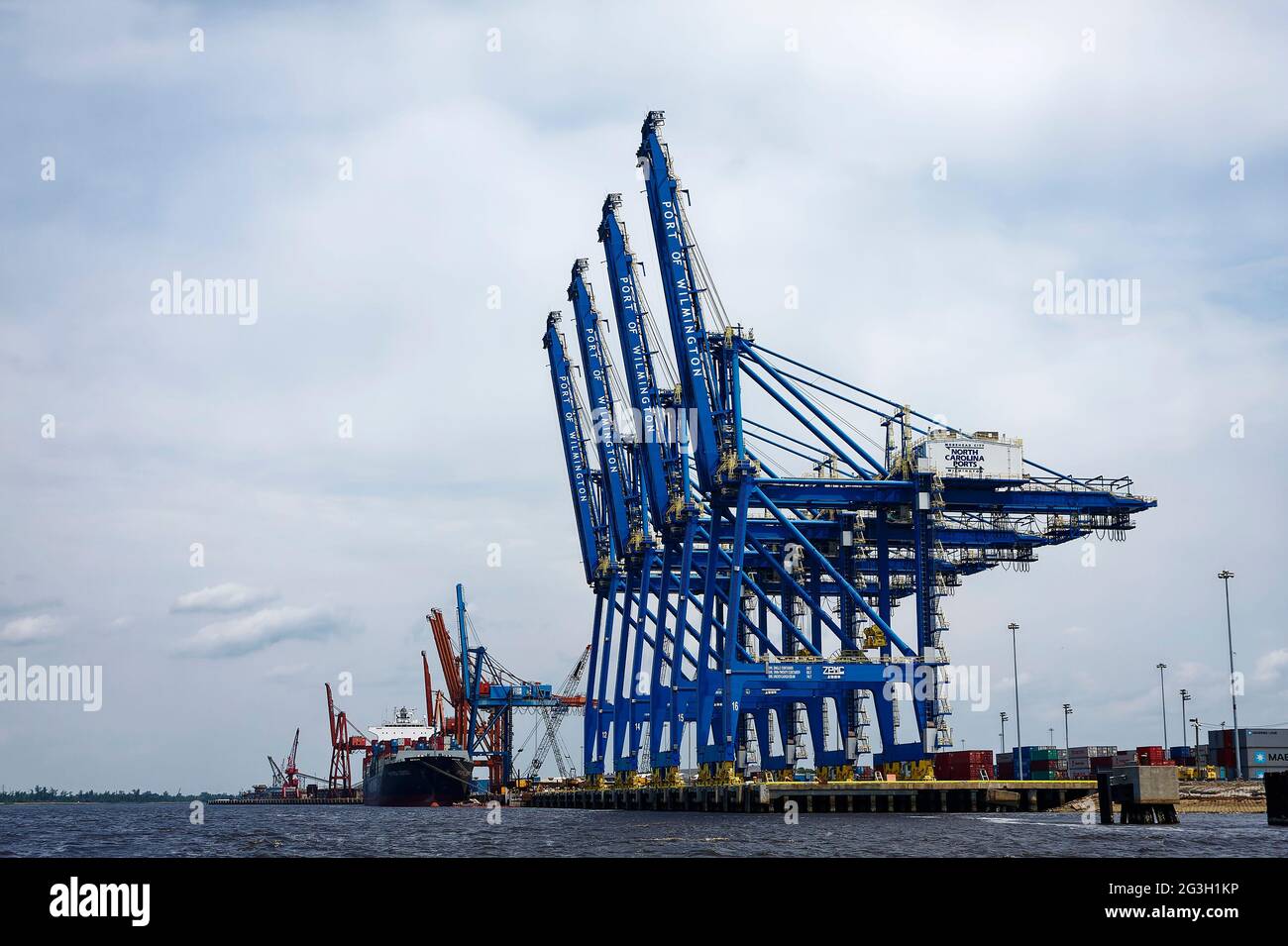 Industrielle Hafenlandschaft, großes Frachtschiff angedockt; Container; Massengutfrachter, Transport; Industrie, Marine, Unternehmen, Güterverkehr, Wasser, Kran Stockfoto