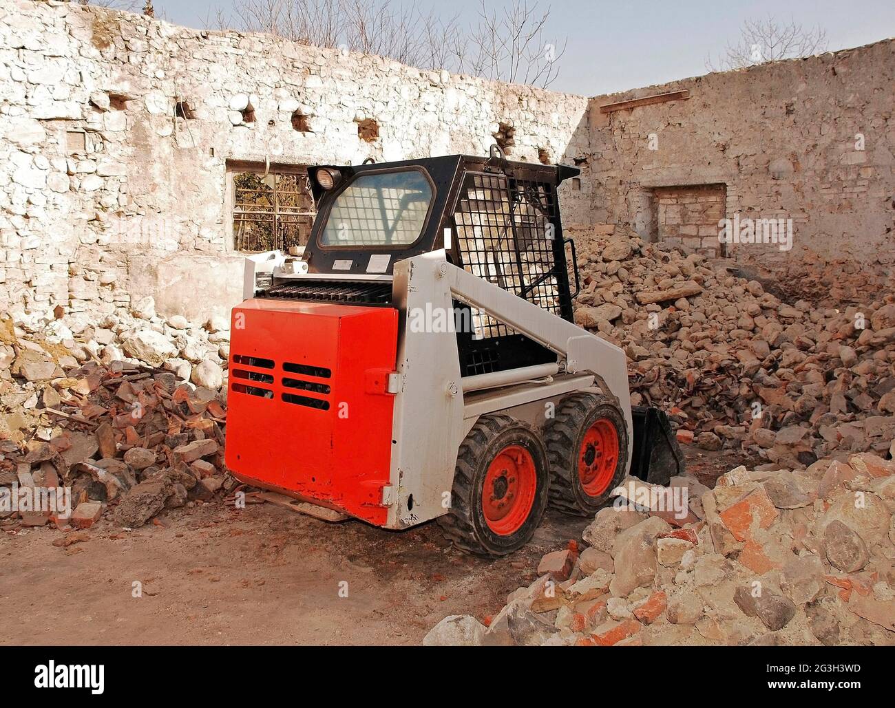 Ein Bobcat-Kompaktlader in einem teilweise abgerissenen alten italienischen Steinbauernhof in der Provinz Udine, Friaul-Julisch Venetien, Nordostitalien Stockfoto